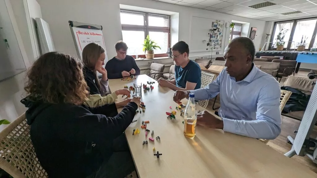 Eine Session Lego Serious Play - die Teilnehmer:innen modellieren am gemeinsamen Tisch mit LEGO. Zunächst jeder für sich.